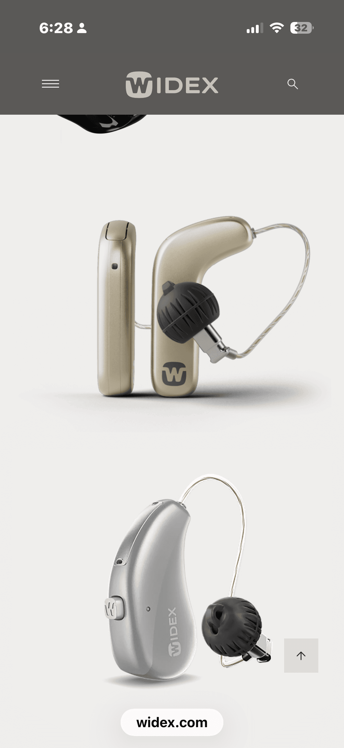 Champagne and silver Widex hearing aids with black domes on a light grey background.
